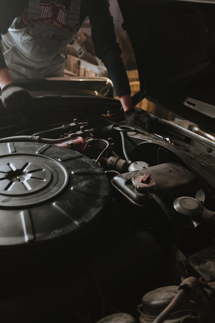 Services Close-up of a mechanic repairing a car engine in a garage setting.