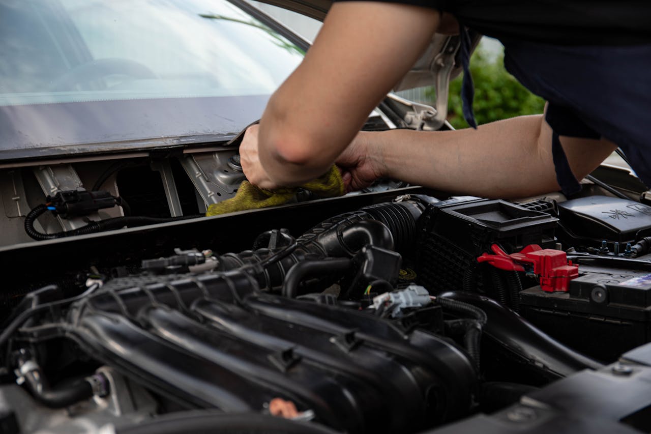 Close-up of a mechanic working on a car engine, showcasing hands and engine details.
